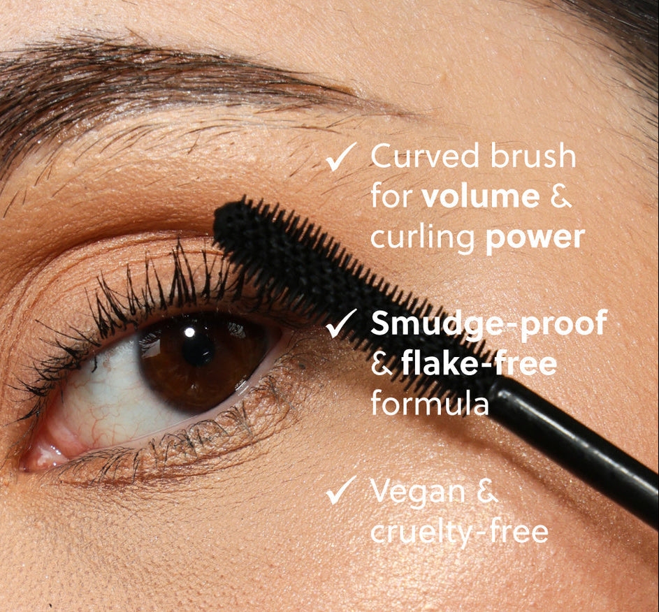 Eyelash mascara being applied with a curved brush, highlighting features like volume, curling power, smudge-proof formula, vegan, and cruelty-free status.